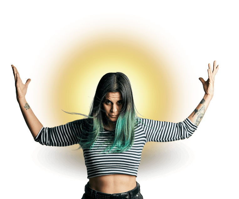 Una mujer con cabello teñido de verde y una camisa a rayas está de pie con los brazos extendidos y un círculo amarillo brillante detrás de ella.