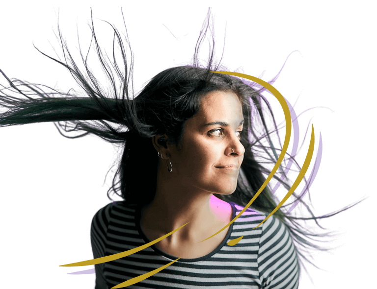 Una mujer con el pelo largo ondeando al viento mira hacia un lado. Lleva una camisa a rayas y hay rayas moradas y amarillas superpuestas a la imagen.